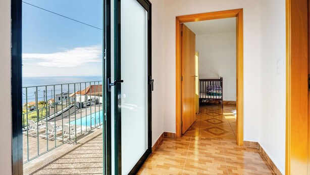 A corridor leading to a balcony with a pool, wooden flooring, and a view of the sea. - Escape to Tranquility in Estreito da Calheta, Portugal (Calheta)