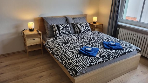 Een slaapkamer met een bed, twee nachtkastjes, een raam en een radiator.