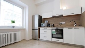 Een moderne keuken met witte kastjes, een inbouwoven, een magnetron en een waterkoker.