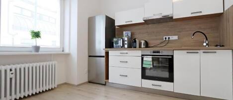 Una cocina moderna con armarios blancos, horno empotrado, microondas y hervidor.