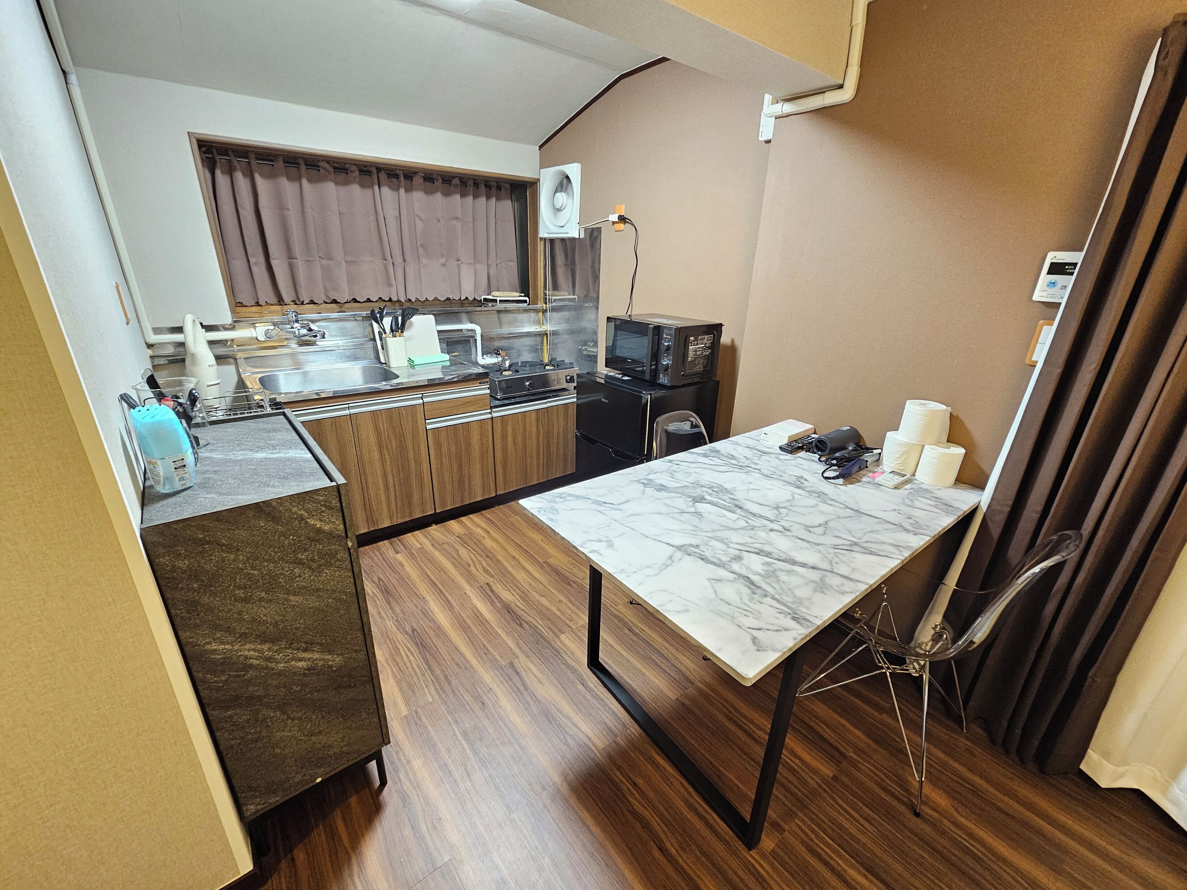 A compact kitchen with a marble countertop, a small dining table, and a microwave.