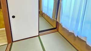 Une pièce de style japonais traditionnel, avec un sol recouvert de tatamis, des portes coulissantes et des paravents en papier de riz (shoji).