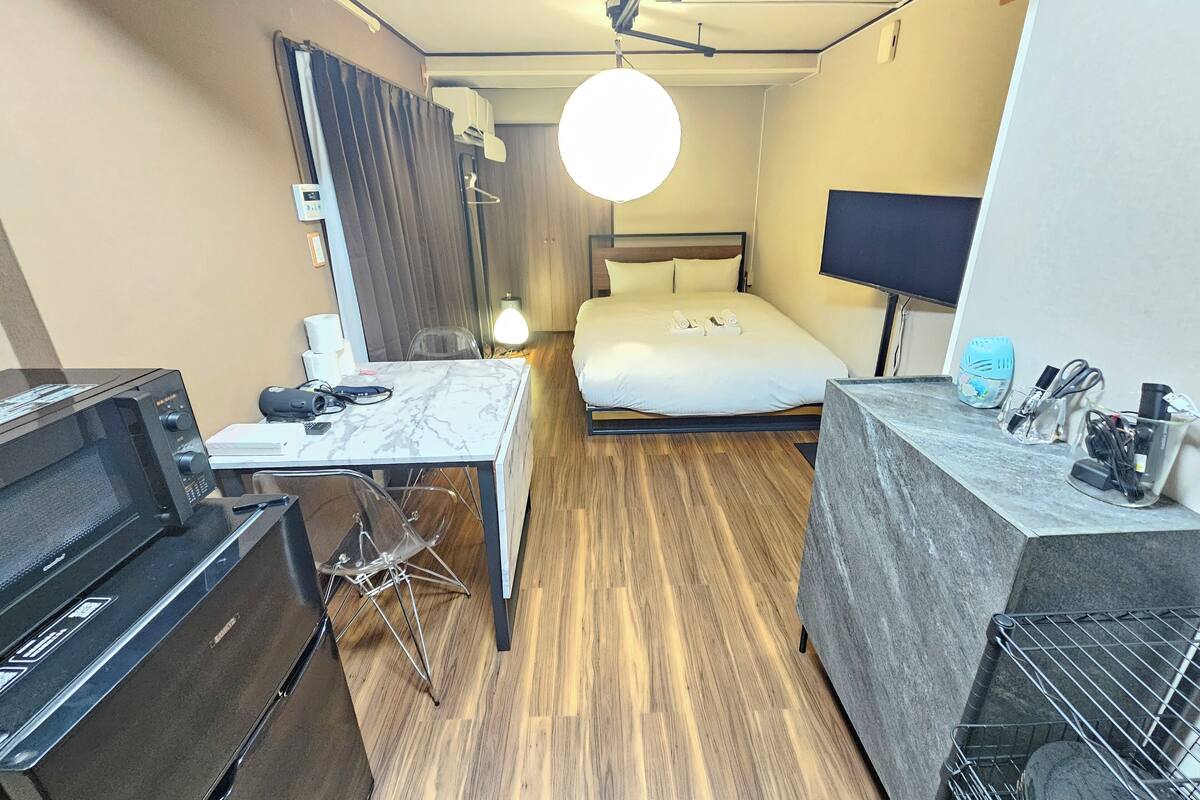 Une chambre d’hôtel compacte comprenant un lit, un bureau, un four à micro-ondes, une télévision et un mini-bar.