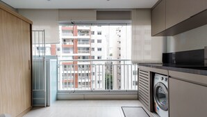 Eine moderne Wohnung mit Balkon, Waschmaschine und Blick auf eine Stadtlandschaft.