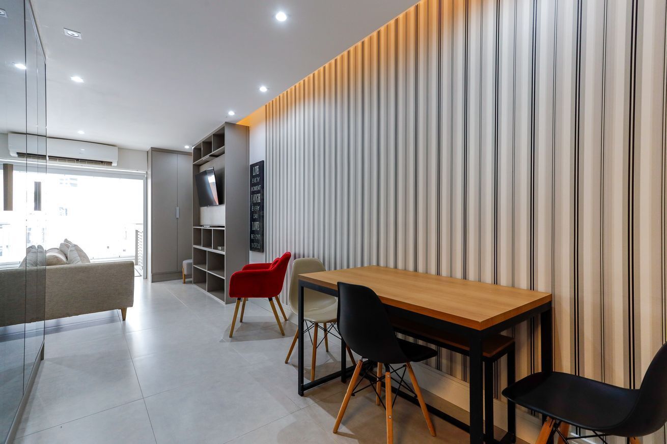 A modern interior with a wooden table and chairs, a sofa, and a striped wall.