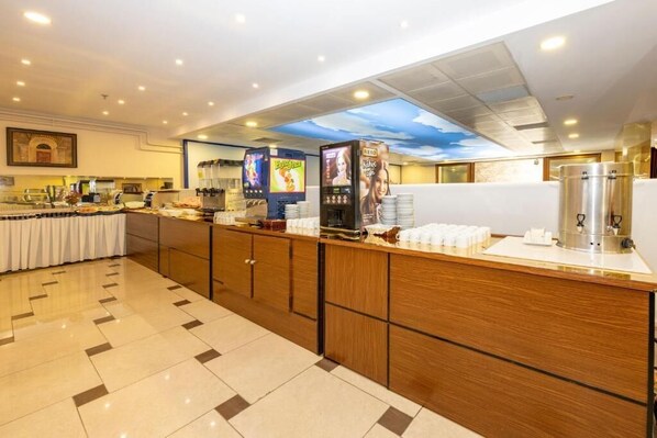A hotel breakfast area with a buffet setup, including a coffee machine, a juice dispenser, and a food display. - Harmoni Hotel Merter & SPA (Istanbul)