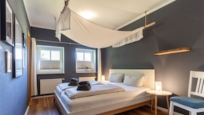 Ein Schlafzimmer mit Bett, Stuhl, Nachttisch und Fenster.