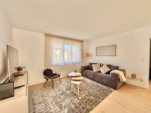 A modern living room with a grey sofa, a small round table, a chair, and a large window. - Apartment Xel-Lac, 4 pers, Annecy (Annecy)