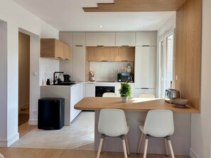 A modern kitchen with white cabinetry, a wooden countertop, and a dining area with two chairs. - Apartment Xel-Lac, 4 pers, Annecy (Annecy)