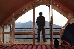 A room with a large window, a wooden ceiling, and a checkered floor.