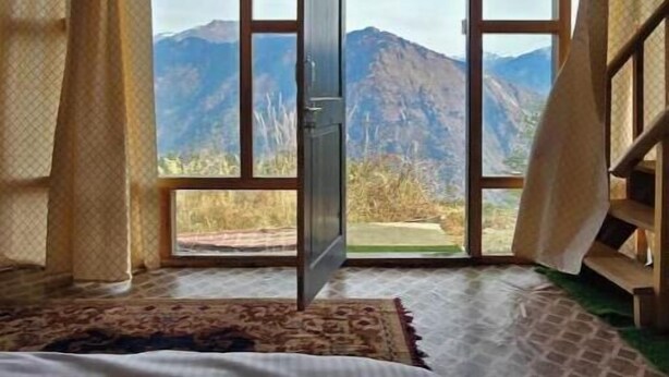 A room with a bed, a window with curtains, and a view of mountains. - The Ridge | Hill Top | Sainjh Valley - TrekNgo, Entire cottage in Sainj, India (Raila)