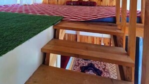 A wooden interior with a bunk bed, a staircase, and a green artificial grass area. - The Ridge | Hill Top | Sainjh Valley - TrekNgo, Entire cottage in Sainj, India (Raila)