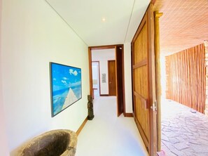 A hallway with a wooden door, a stone sculpture, and a framed picture on the wall. - House inside the Tivoli Eco-Resort in Praia do Forte - nature at your feet! (Açu da Torre)