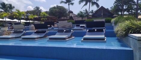 A pool area with lounge chairs and a tiled pool.