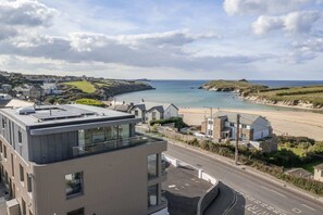 A coastal town with modern buildings, a beach, and a clear view of the sea. - Modern Apartment with Balcony, Sea Views & Parking (Newquay)