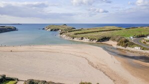 Eine Küstenlandschaft mit sandigem Strand, Grasflächen und einer sich an der Küste entlang schlängelnden Straße.