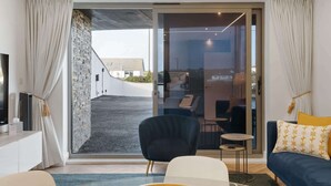 A modern living room with a sofa, a chair, a small table, and a TV. There is a sliding glass door leading to an outdoor area. - Groundfloor Apartment, Easy Access Private Parking (Newquay)