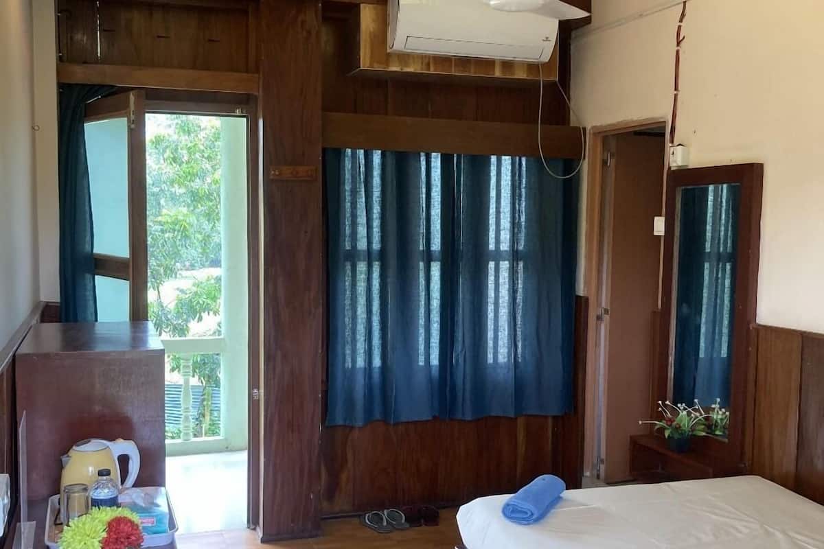 Habitación de hotel con cama, escritorio, ventilador de techo y ventana con cortinas.