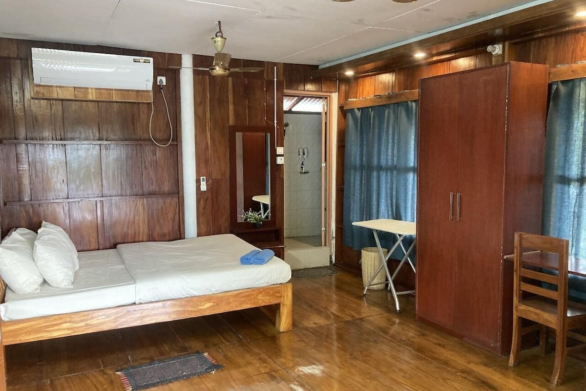 Una habitación con cama de madera, un escritorio y un armario.