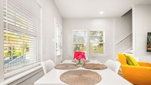 A dining area with a white table, white chairs, and woven placemats. - 3 Bedrooms | Downtown Pensacola | Walkable Location | Fenced Yard (Pensacola)