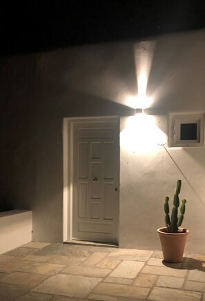 Ein Eingang mit Leuchte darüber, einem Topf mit Kaktee und einem kleinen Fenster an der Wand.