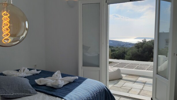 Ein Schlafzimmer mit einem Bett, einem Handtuch und Blick ins Freie durch eine Glasdoor.