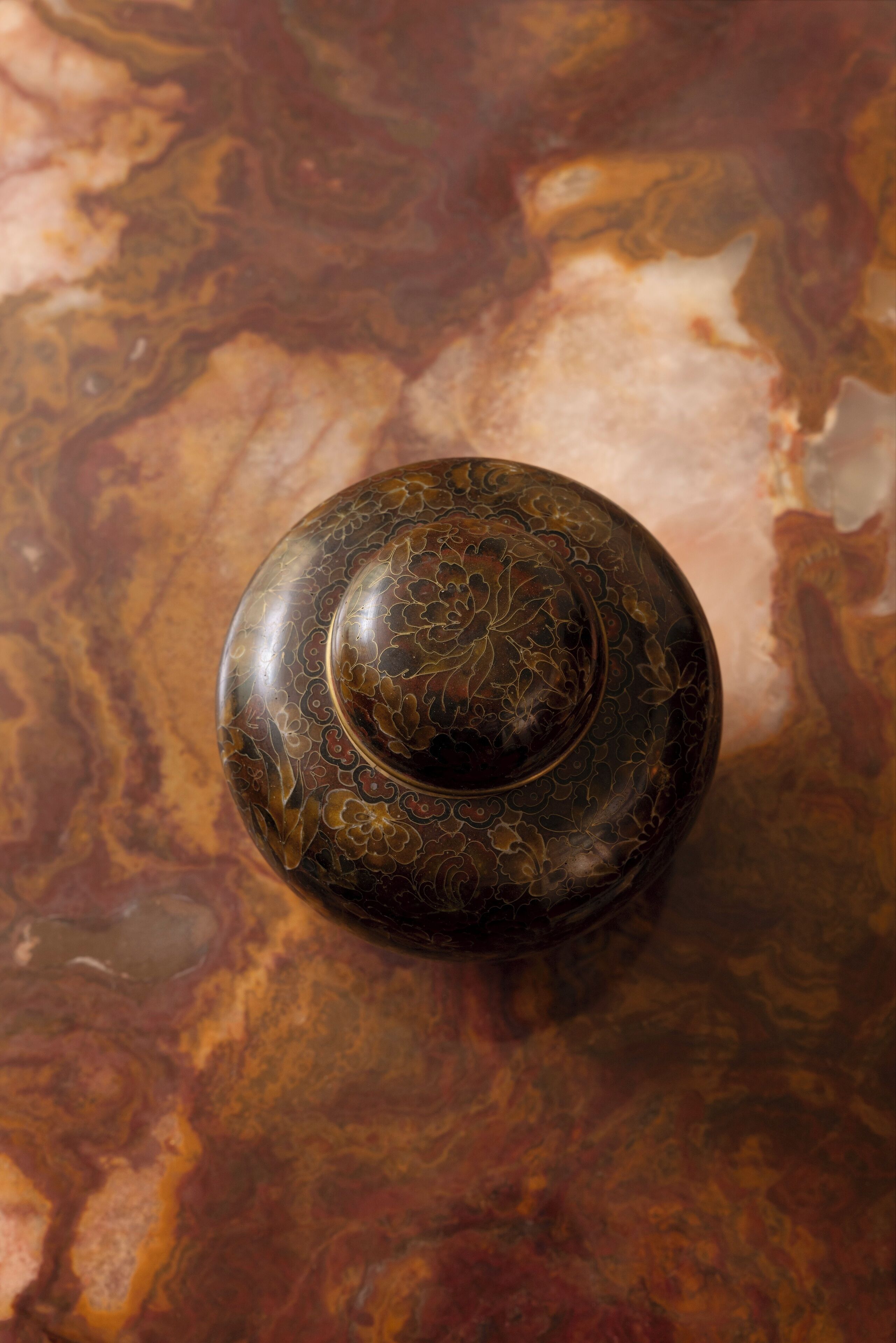 A round, ornate object with intricate patterns, placed on a marbled surface.