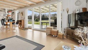 Amplia sala de estar con un gran ventanal corredero que da a un patio, una cocina con electrodomésticos modernos y un comedor con mesa y sillas.
