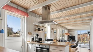 Una cocina moderna con techo de madera, un ventanal grande y un comedor con vistas.