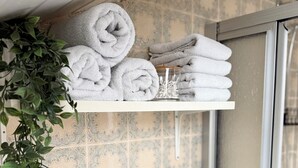 Estante con toallas ordenadamente dobladas y una planta decorativa.