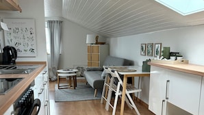 Una cocina moderna con tragaluces, un comedor con sofá gris y una mesa pequeña.