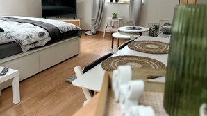 Un dormitorio moderno con una cama, un televisor, una mesita y una silla.