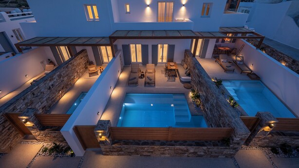 A modern villa with a rooftop pool, outdoor seating area, and a stone wall. - Ios Art Suites (Ios)