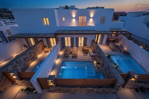 Una villa moderna con piscina sul tetto, area salotto esterna e un muro in pietra.