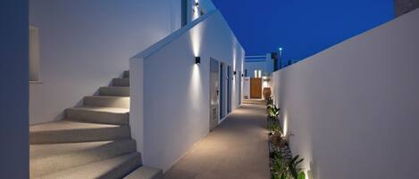 A modern building with a narrow, well-lit corridor leading to a staircase.