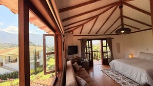 Un dormitorio con una cama grande, un sofá, un televisor y vistas a un paisaje montañoso.