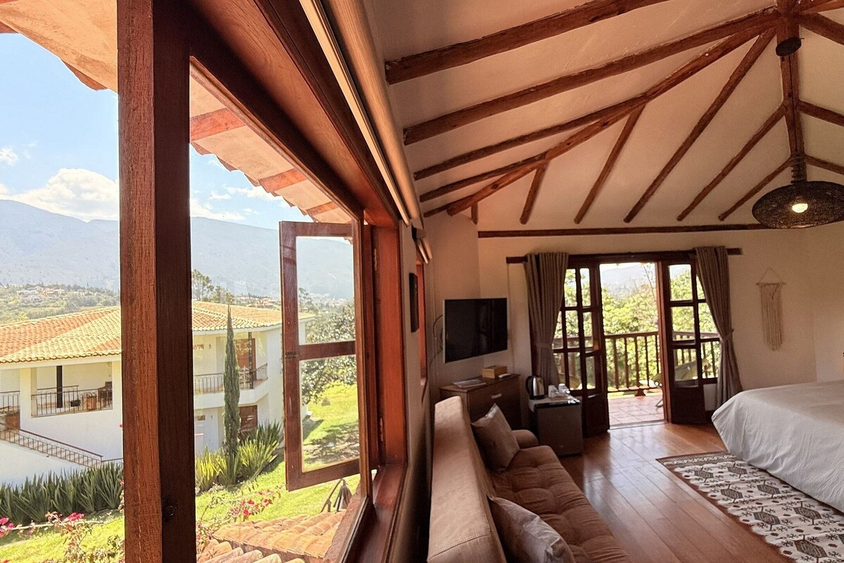 Un dormitorio con una cama grande, un sofá, un televisor y vistas a un paisaje montañoso.