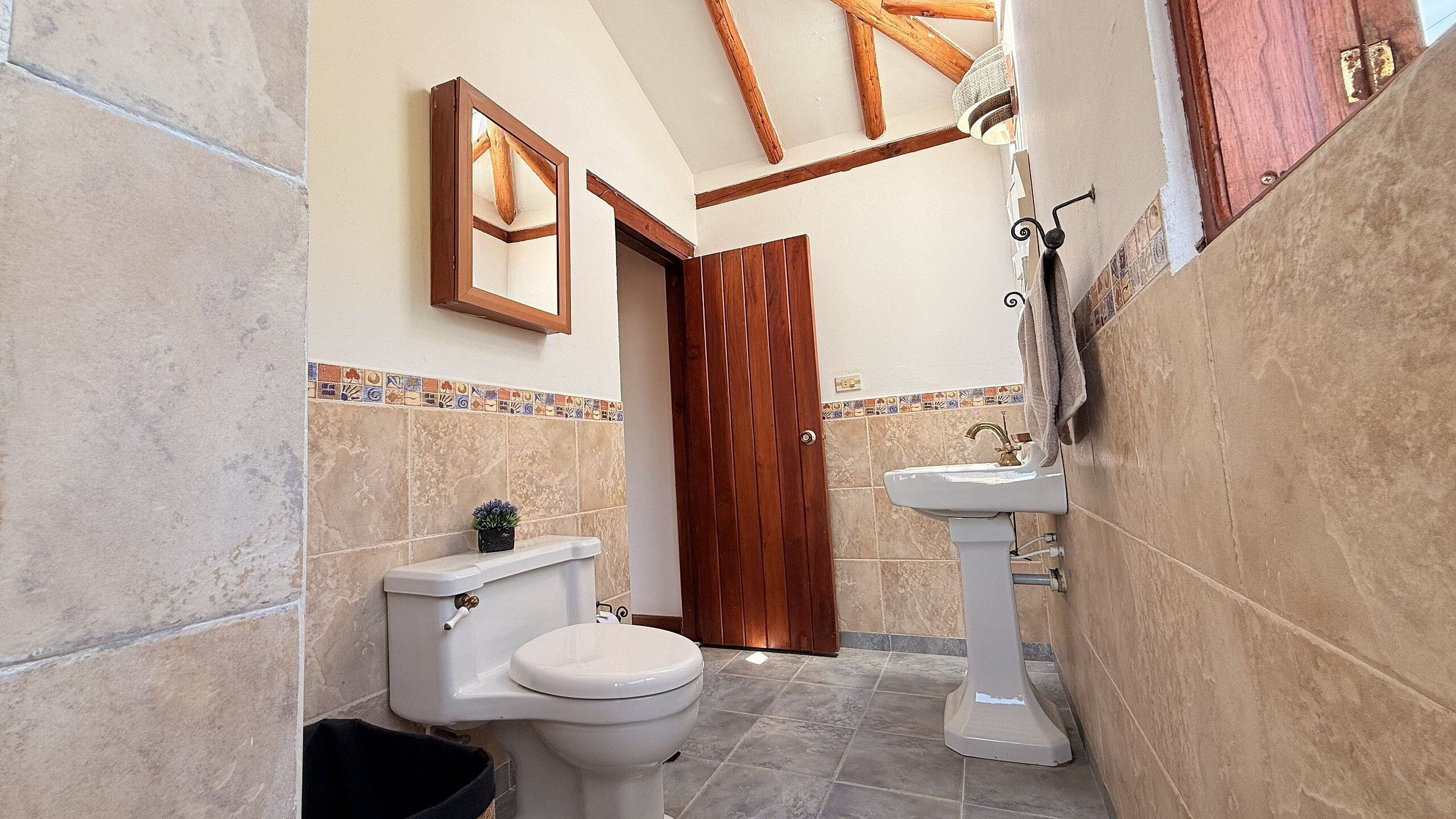 Un baño pequeño con inodoro, lavabo y puerta de madera.