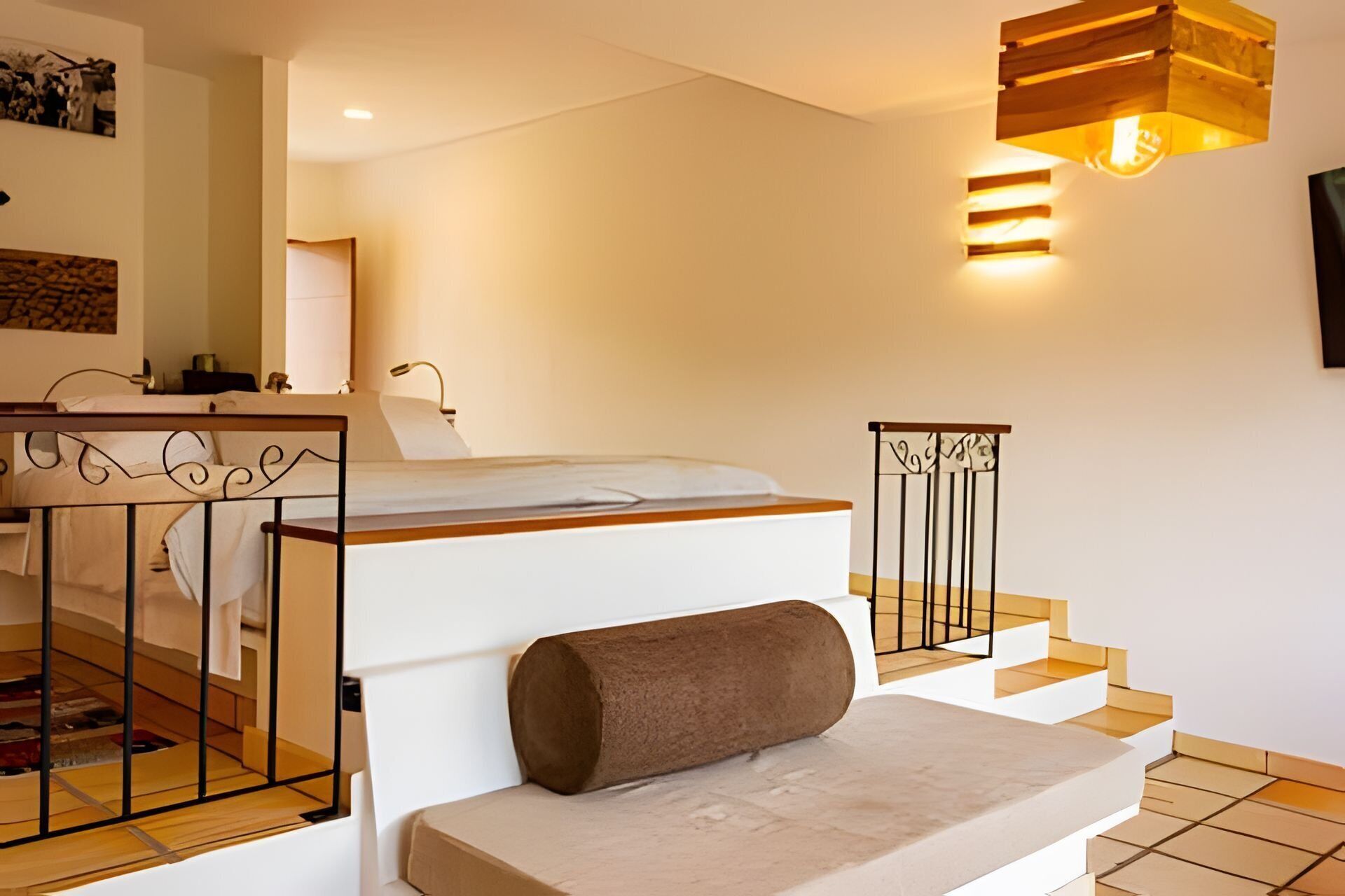 A modern bedroom with a bed, a bedside table, a lamp, and a staircase.