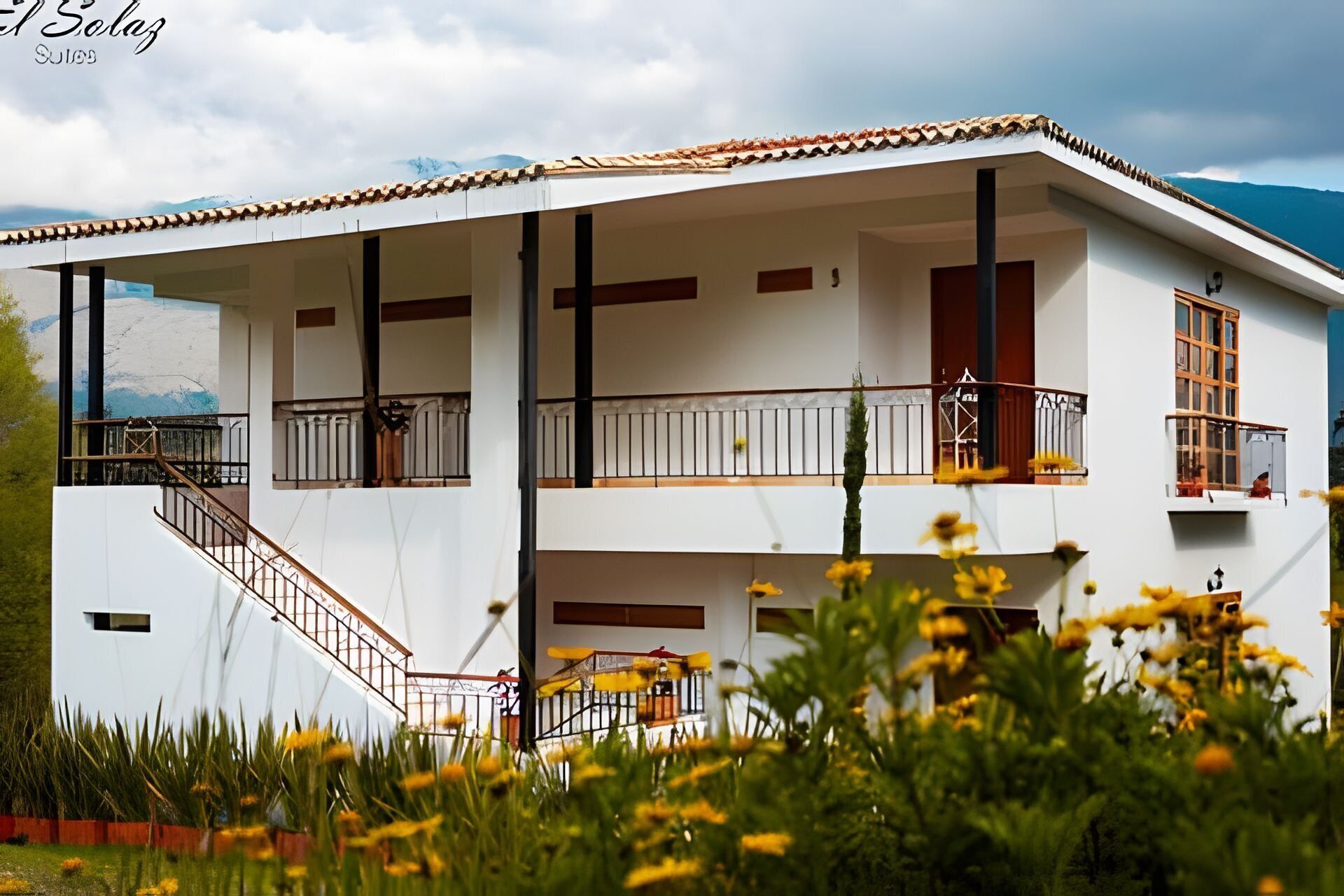 A two-story building with a white facade, balconies, and a staircase leading to the upper floor.