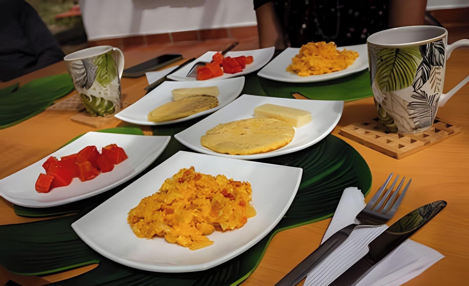 A table with plates of food, a cup, and cutlery.