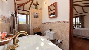 Un baño con bañera, inodoro y ducha. Hay una ventana con vistas al exterior.