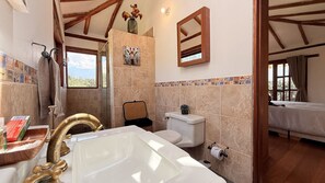 Un baño con bañera, inodoro y ducha. Hay una ventana con vistas al exterior.