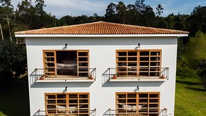 Un edificio de dos plantas con tejado de tejas, varios balcones con barandillas y ventanas amplias.