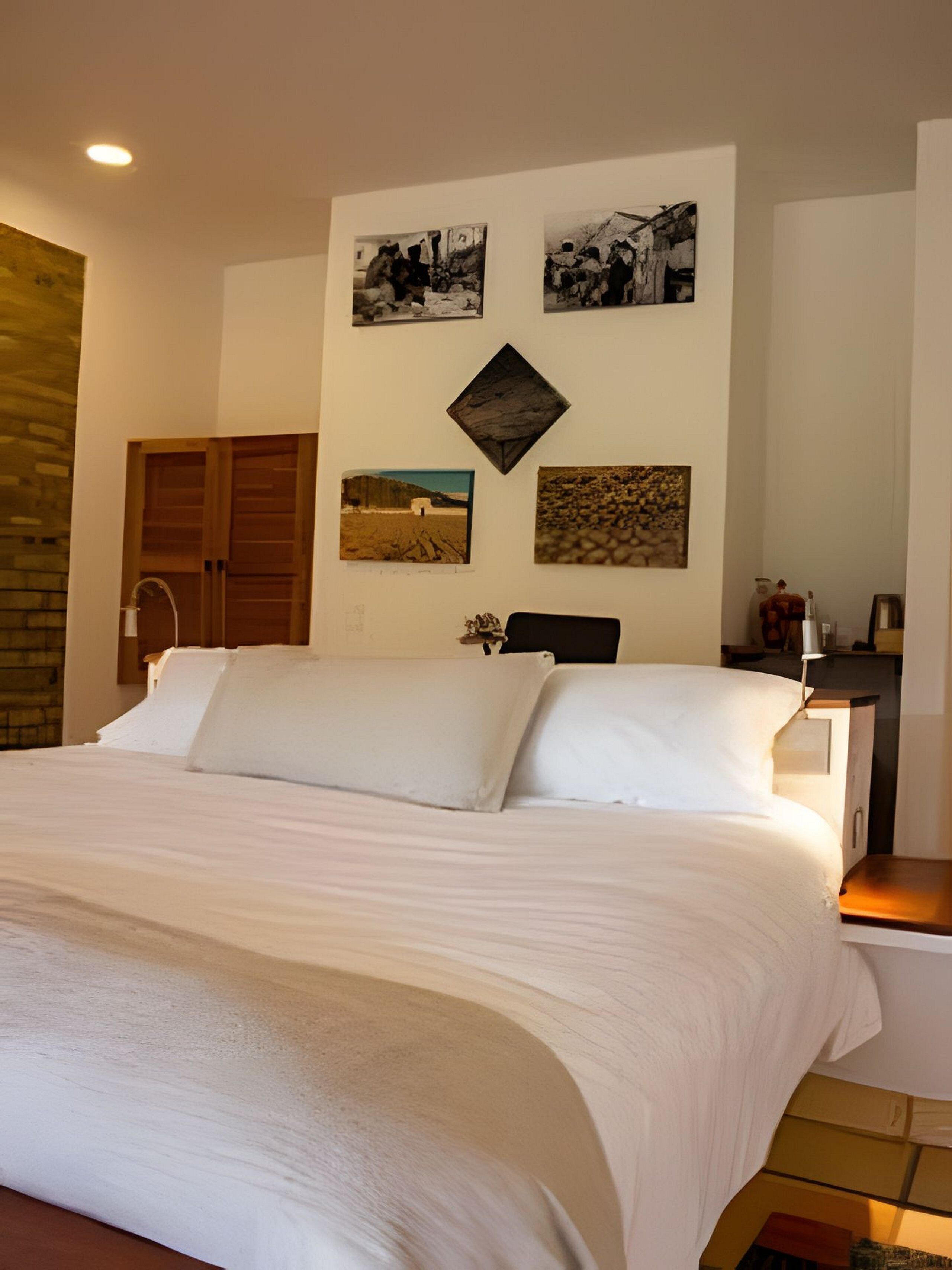 A bedroom with a large bed, a wooden wardrobe, and a nightstand with a lamp.
