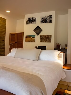 A bedroom with a large bed, a wooden wardrobe, and a nightstand with a lamp. - El Solaz By Honnor Living   (Villa de Leyva)