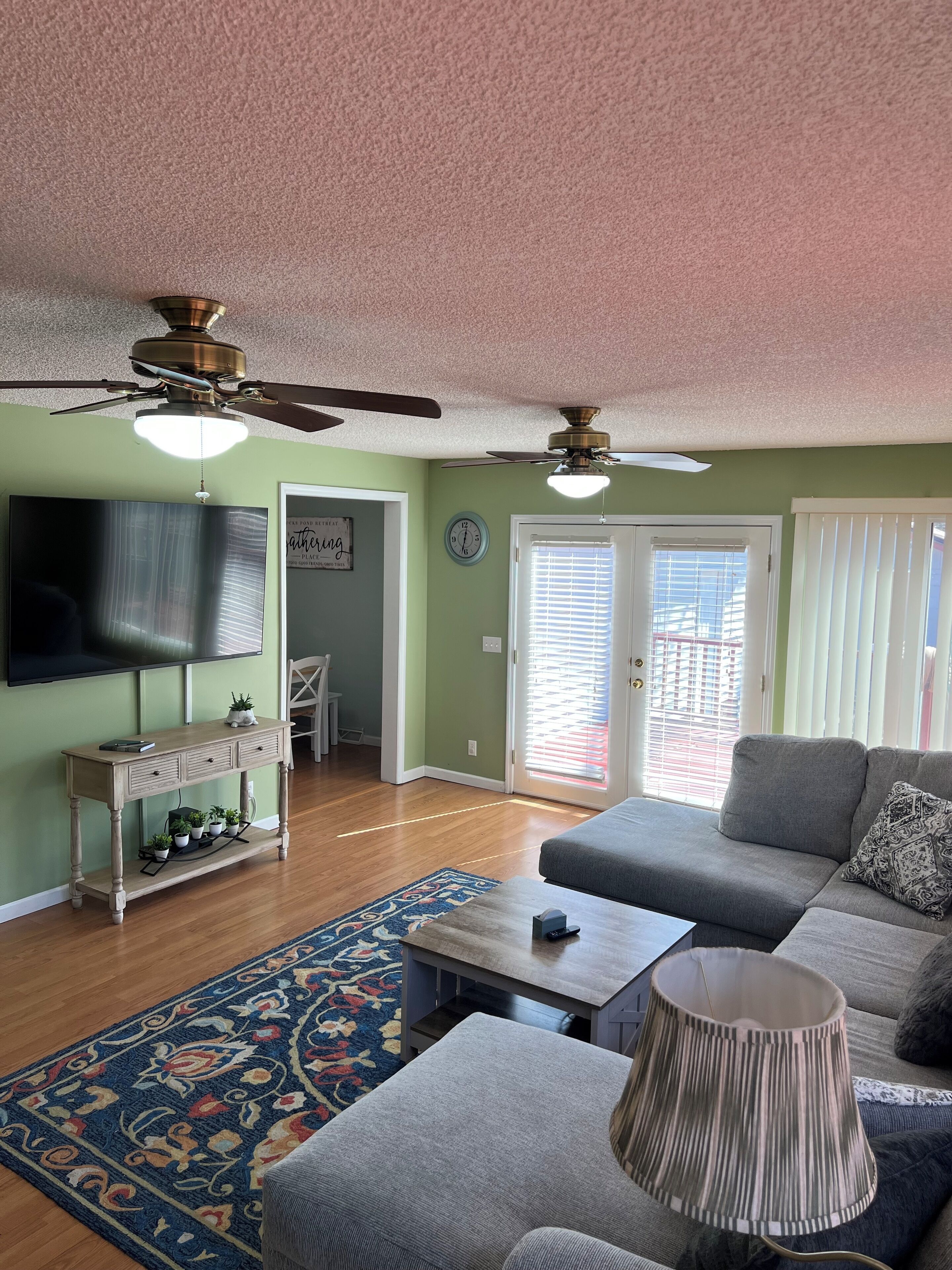A living room with a sofa, coffee table, TV, and ceiling fans.