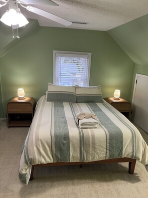A bedroom with a bed, two bedside lamps, a window, and a ceiling fan. - Rocks Pond Retreat- Waterfront, Private Boat Launch, Dock (Eutawville)