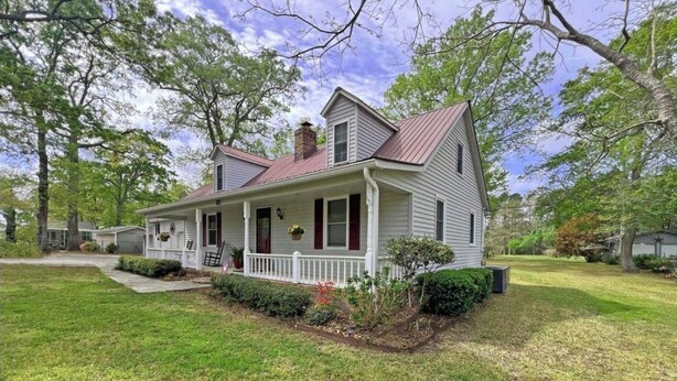 A two-story house with a front porch, a chimney, and a well-maintained lawn.