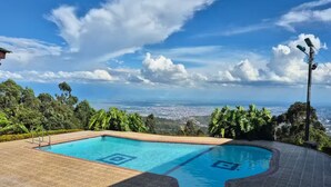 Une piscine offrant une vue sur le paysage urbain et les montagnes en arrière-plan.
